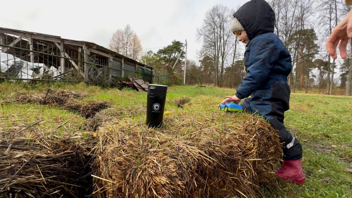 Ребёнок играет на стоге сена, чашка кофе на фоне осеннего утра в Звенигороде